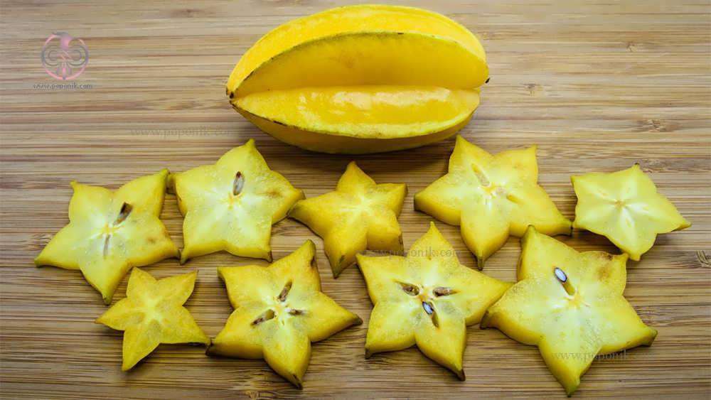 مقداری میوه ستاره پوست کنده شده کنار میوه ستاره روی زمین چوبی