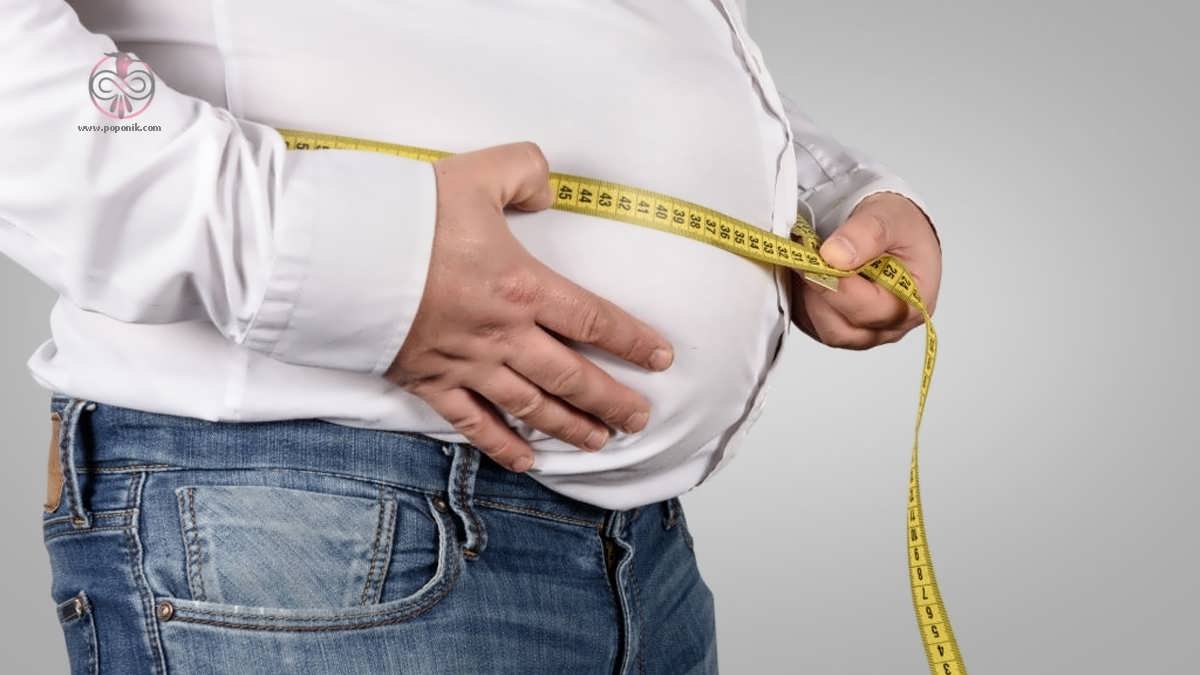 مردی با اضافه وزن در حال اندازه گرفتن شکم خود با متر